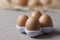 Brown or yellow Fresh farm eggs on quaternary eggcup, eggs background