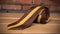 a brown and yellow striped tie laying on a wooden floor next to a brick wall and a brick wall in the back ground of a room