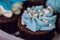 Brownie cupcake muffin with blue whipped cream twirl and white pearl beads topping