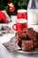 Brownie pieces with nuts on the plate, two cups of milk and bottle. Christmas tree.