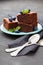 Brownie stack decorated blueberries and green mint leaves. Chocolate cake in turquoise plate on vintage black table. Homemade past