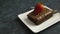 Brownie with strawberry on plate on textured background