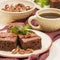 Brownie sweet chocolate dessert with walnuts and meant leaves on craft plate and cup of black coffee.