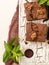 Brownie sweet chocolate dessert with walnuts and meant leaves on retro board with copy space on pastel beige background.