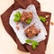 Brownie sweet chocolate dessert with walnuts and meant leaves on white paper with copy space on pastel beige background.