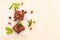Brownie sweet chocolate dessert with walnuts and meant leaves on white paper with copy space on pastel beige background.