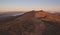 A brownish orange mountain meadow at sunrise with inversion of clouds in the background in Bieszczady Mountains