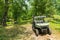 BRP Can-Am Traxter buggy in green Caucasus mountain forest. ATV and SSV travel adventure and nature exploration concept