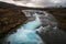 Bruarfoss waterfall in Icelandic scenery during sunset and cloudy sky. Turquoise cascade and golden warm light