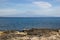 Brucoli view of sea from rocky coast, the distant Etna volcano and the blue sea and sky