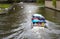 Bruges, Belgium - October 11 2019: Tourist boat goes under rain on canal with swans near Begijnhof