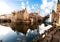 Brugge, Belgium: Medieval houses and gothic bell tower reflecting on water, during a sunny winter day.