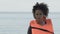 Bruised Afro-American girl in life vest looking at camera, plane crash victim