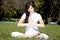 Brunet yoga girl on green grass in park.