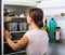 Brunette in apron looking at products in refrigerator