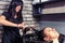 Brunette attractive hairdresser combing hair of young beautiful