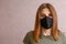 brunette in a black mask. a young woman in a cloth mask on a light background. protection against coronavirus infection, covid-19