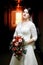 Brunette bride with bouquet standing in hotel hallway, tunnel light.