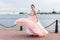 Brunette caucasian model whirling around in flying long pastel pink dress on quay