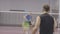 Brunette Caucasian sportsmen playing badminton in gym. Middle shot of confident athletic men training indoors. Live