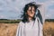 Brunette Caucasian young woman with windy blowing hair outside, against meadow and sky. Portrait of dream female looking away with