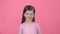 Brunette child smiling on pink background. Slow motion