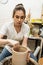 Brunette craftswoman in apron shaping clay