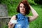 Brunette in a denim dress with a white cup on a saucer in hand corrects the hairstyle.