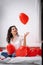 Brunette European girl rejoices playing on bed with red heart shape balloons. Morning love surprise gift on valentines