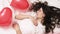 Brunette European girl sleeping on bed with red heart shape balloons.Morning surprise gift on valentines day