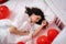 Brunette European girl sleeping on bed with red heart shape balloons.Morning surprise gift on valentines day