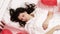 Brunette European girl sleeping on bed with red heart shape balloons.Morning surprise gift on valentines day