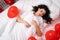 Brunette European girl sleeping on bed with red heart shape balloons.Morning surprise gift on valentines day