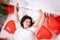Brunette European girl wake up on bed with red heart shape balloons. Morning love surprise gift on valentines day
