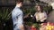 Brunette, european saleswoman wearing apron helping with a customer`s choice, putting a pile of green salad in brown