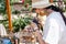 a brunette european woman in a white T-shirt and hat takes pictures of her goods at a street fair