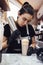 Brunette female barista decorates milk cocktail with cream using pastry nozzle