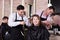 Brunette getting haircutting from two hairstylists