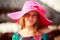 brunette girl in big red hat looks down at defocused background