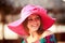 brunette girl in big red hat smiles winks at defocused umbrella