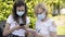 Brunette girl and blonde woman busy using smartphone and tablet with the protective mask against the risk of coronavirus covid-19