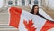 Brunette girl with Canada Flag in Her Hands Smiling