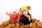 Brunette girl in cap with bobbles lying on autumn leaves by flowers