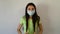 A brunette girl demonstrates a medical mask and puts the mask on her nose and mouth. Straightens her hair. Gives a thumbs up.