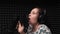 Brunette girl emotional singing to microphone in vocal studio. Talented young female artist is recording song with professional mu