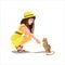 Brunette girl in a hat and yellow dress sits and holds out her hand to the kitty. Cute brown kitty. Cute girl in beautiful dress.