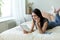 Brunette girl lying on the bed in a bright room reading a book