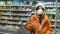 Brunette girl in medical mask at the grocery store. pandemic