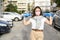 A brunette girl in protective gloves shows a medical mask that is on her face. She is standing on the street. The concept of self-