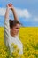 Brunette girl in rapeseed field  summer time, facing side way blue sky background.